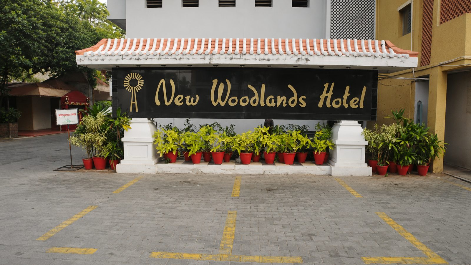 Entrance of New Woodlands Hotel with its gold signage and terracotta-tiled canopy